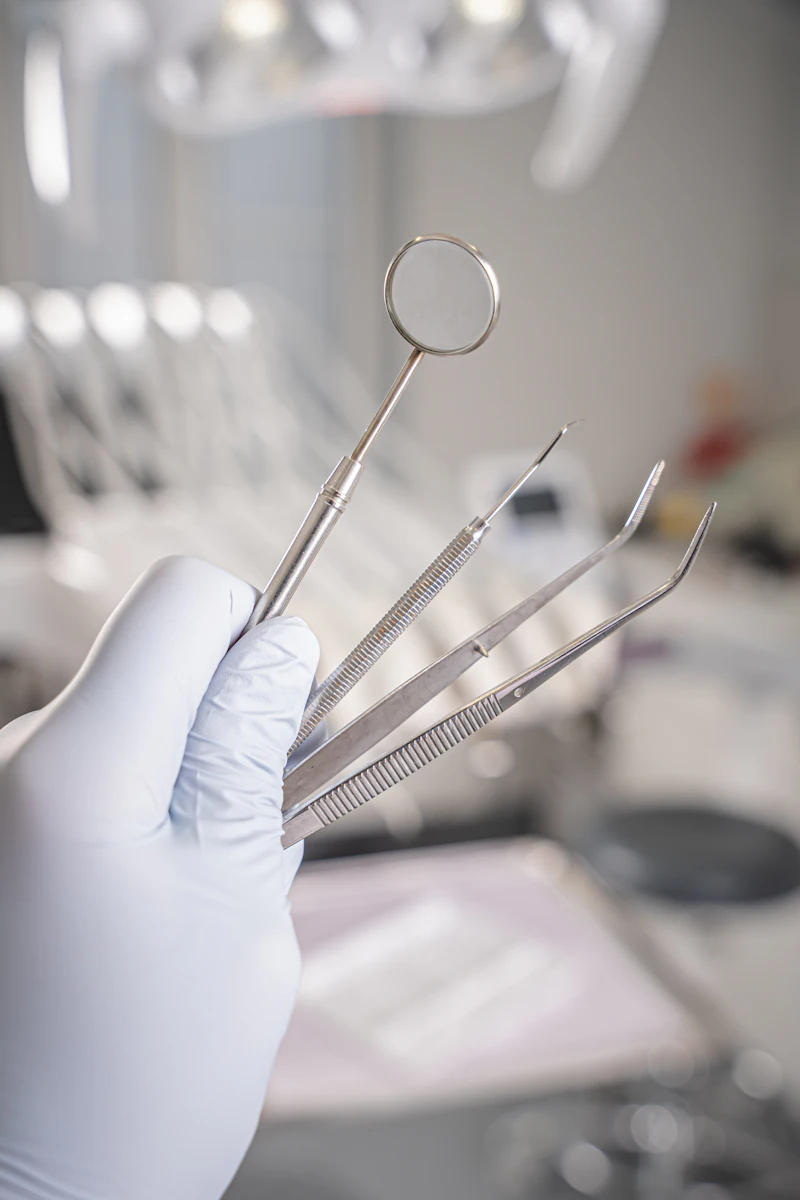 A gloved hand holding small dental check-up tools