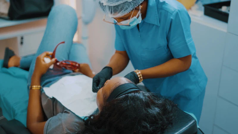 A dentist in blue scrubs treating a patient lying back in the chair